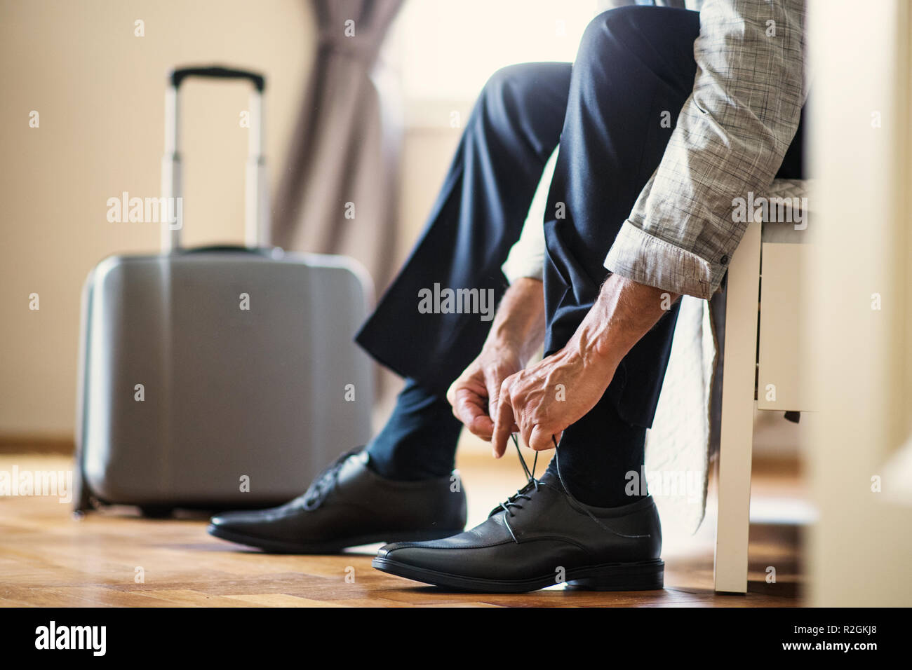 Sezione mediana di imprenditore su un viaggio di affari seduto in una stanza di un hotel, di legatura lacci delle scarpe. Foto Stock