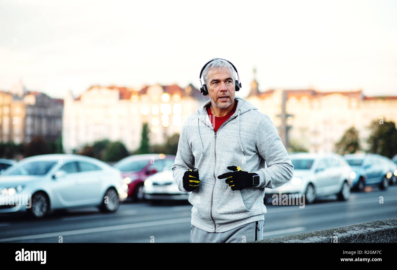 Maschio maturo runner con cuffie in esecuzione all'aperto sul ponte nella città di Praga. Foto Stock