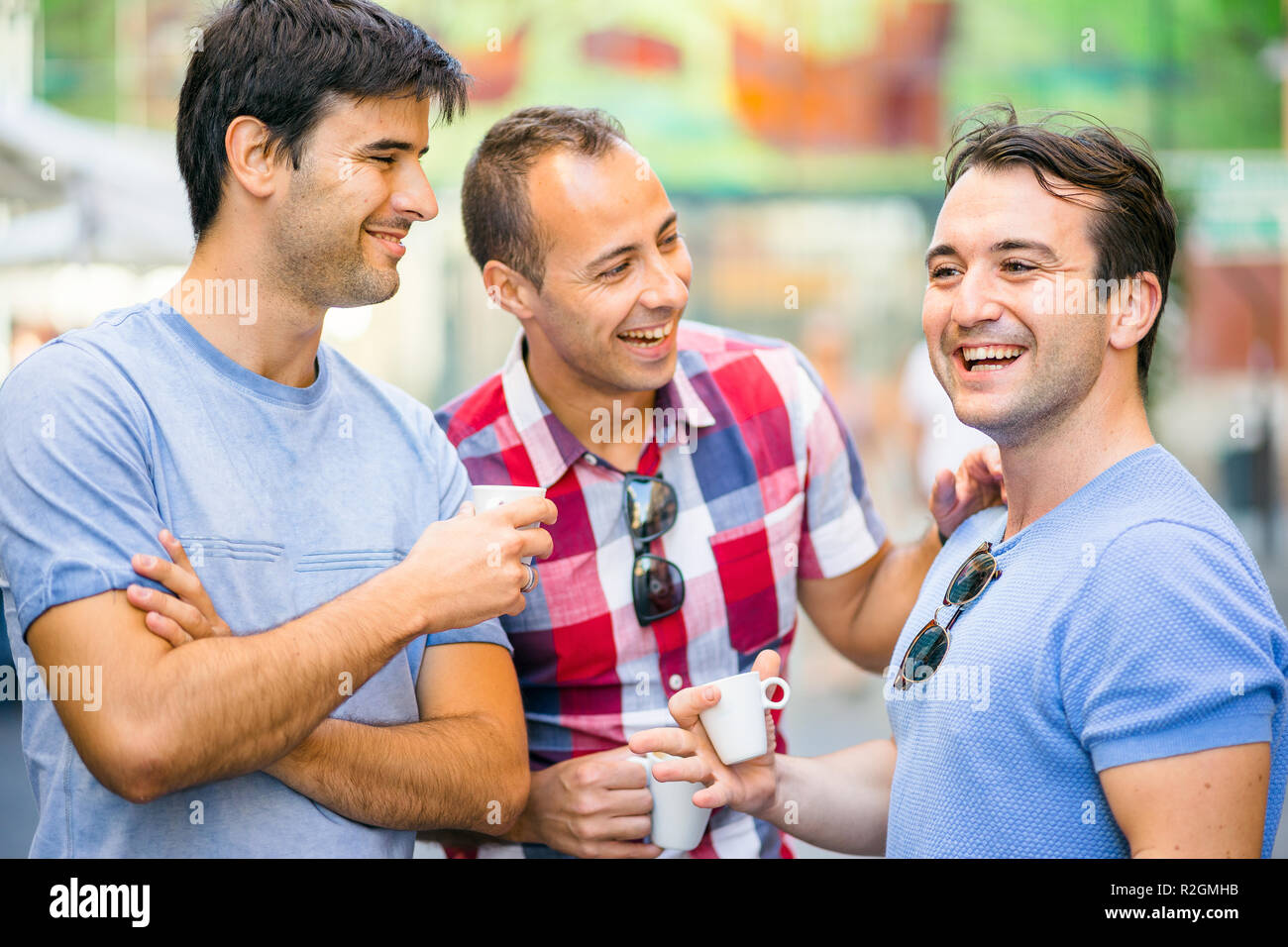 Tre amici a parlare e divertirsi mentre si beve il caffè all'aperto Foto Stock