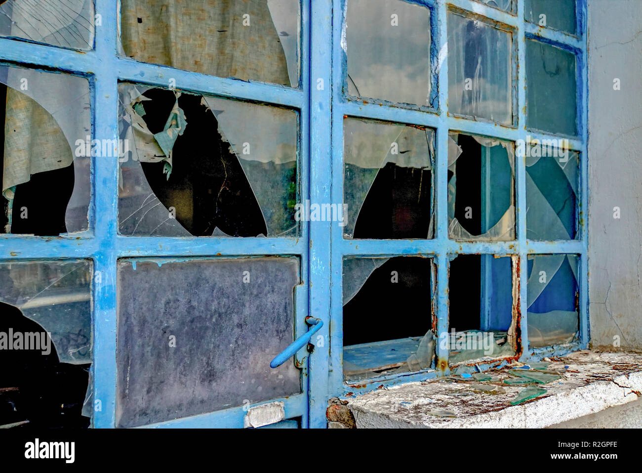 Abbandonata e fatiscente negozio di fronte per la rottura di vetri. Le difficoltà economiche e la depressione. Fotografato a Atene, Grecia Foto Stock