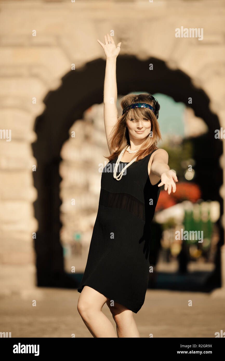 Enca ragazza divertirsi ballare sulla strada.. Stile retrò vintage moda donna in abito nero dal fragore 1920s all'esterno. Città Vecchia di Danzica Danzica nel Foto Stock