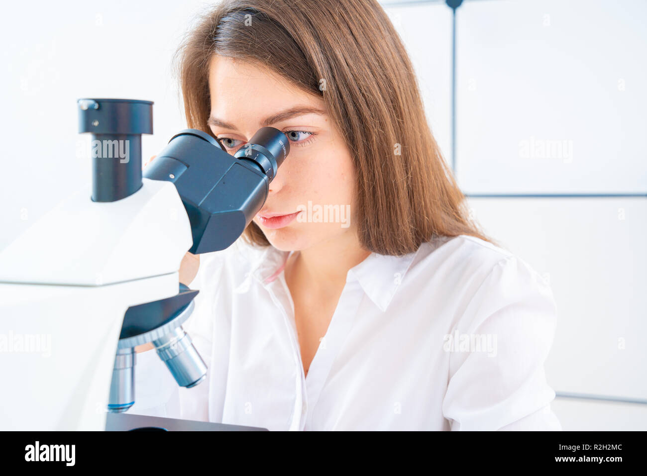 Scienziato analizzando vetrino del microscopio in laboratorio. Giovane donna tecnico sta esaminando un campione istologico, una biopsia in laboratorio di cancro ri Foto Stock