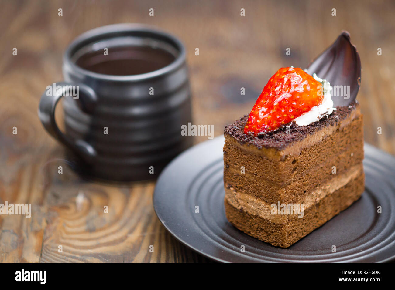 Fetta di torta al cioccolato nel piattino accanto alla tazza di caffè sul legno invecchiato Foto Stock