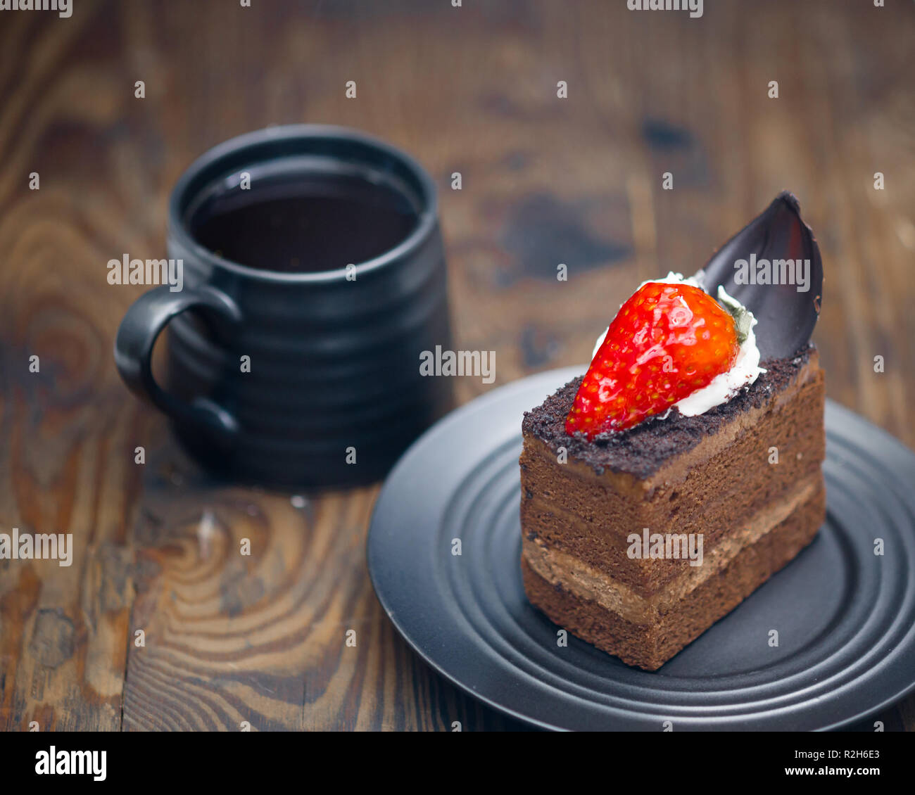 Fetta di torta al cioccolato nel piattino accanto alla tazza di caffè sul legno invecchiato Foto Stock