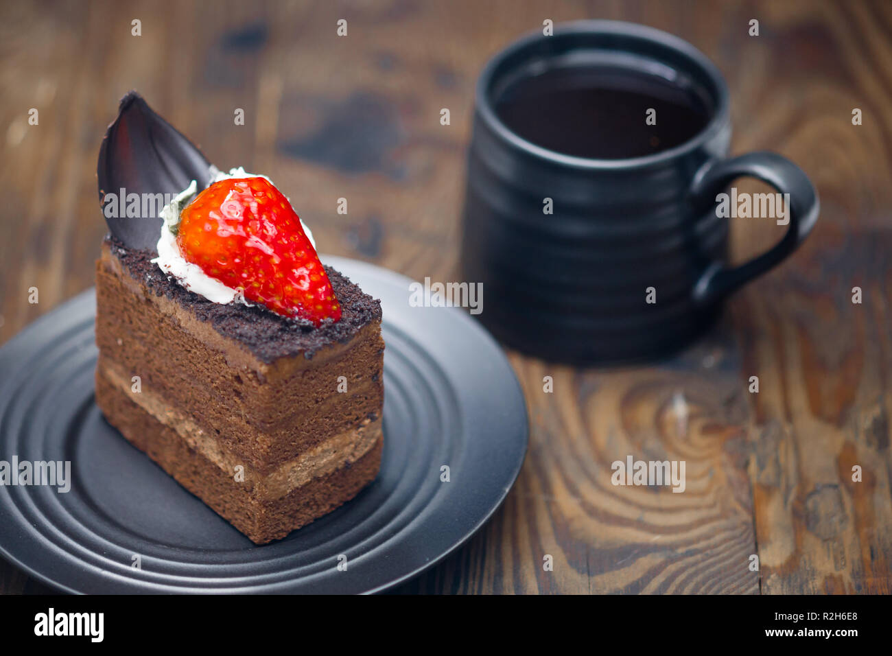 Fetta di torta al cioccolato nel piattino accanto alla tazza di caffè sul legno invecchiato Foto Stock