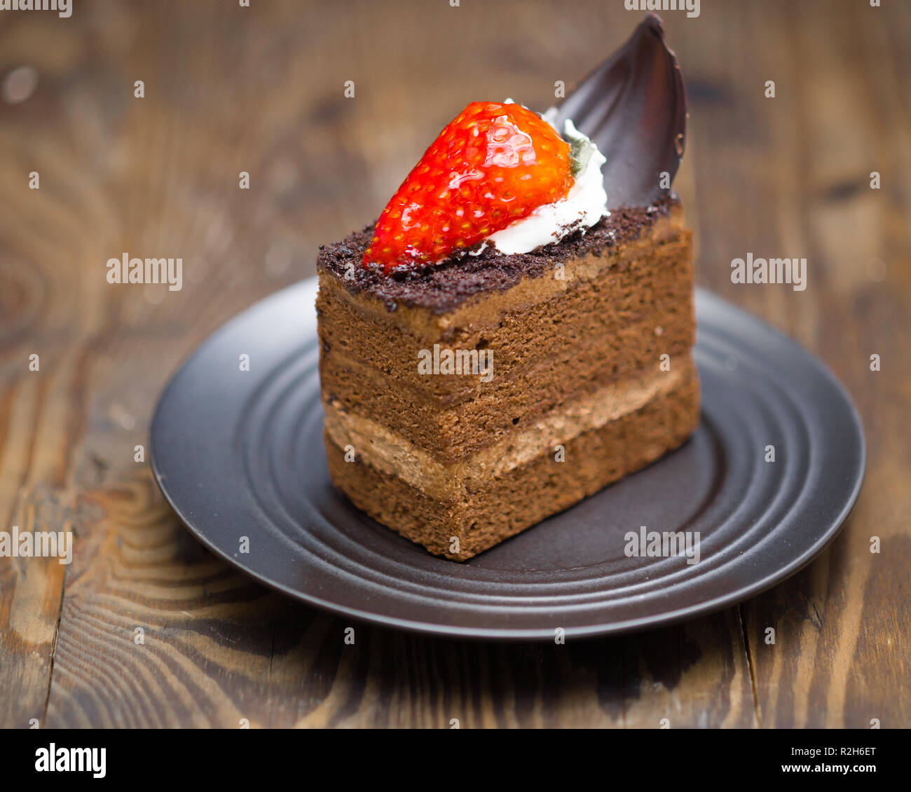 Fetta di torta al cioccolato nel piattino in legno invecchiato Foto Stock