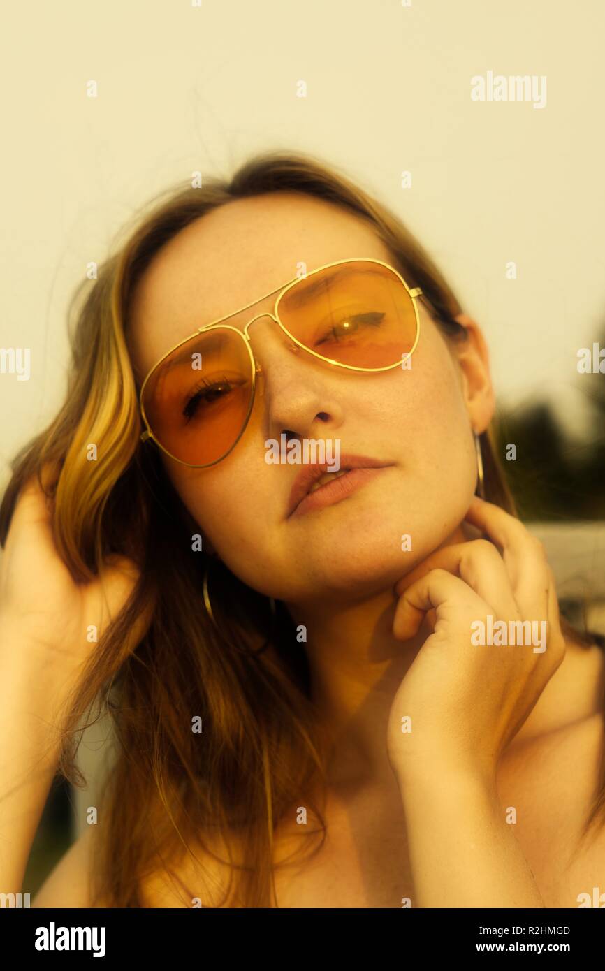 Ritratto di giovane donna che indossa arancione occhiali da sole oscurata con un 70's vibe Foto Stock