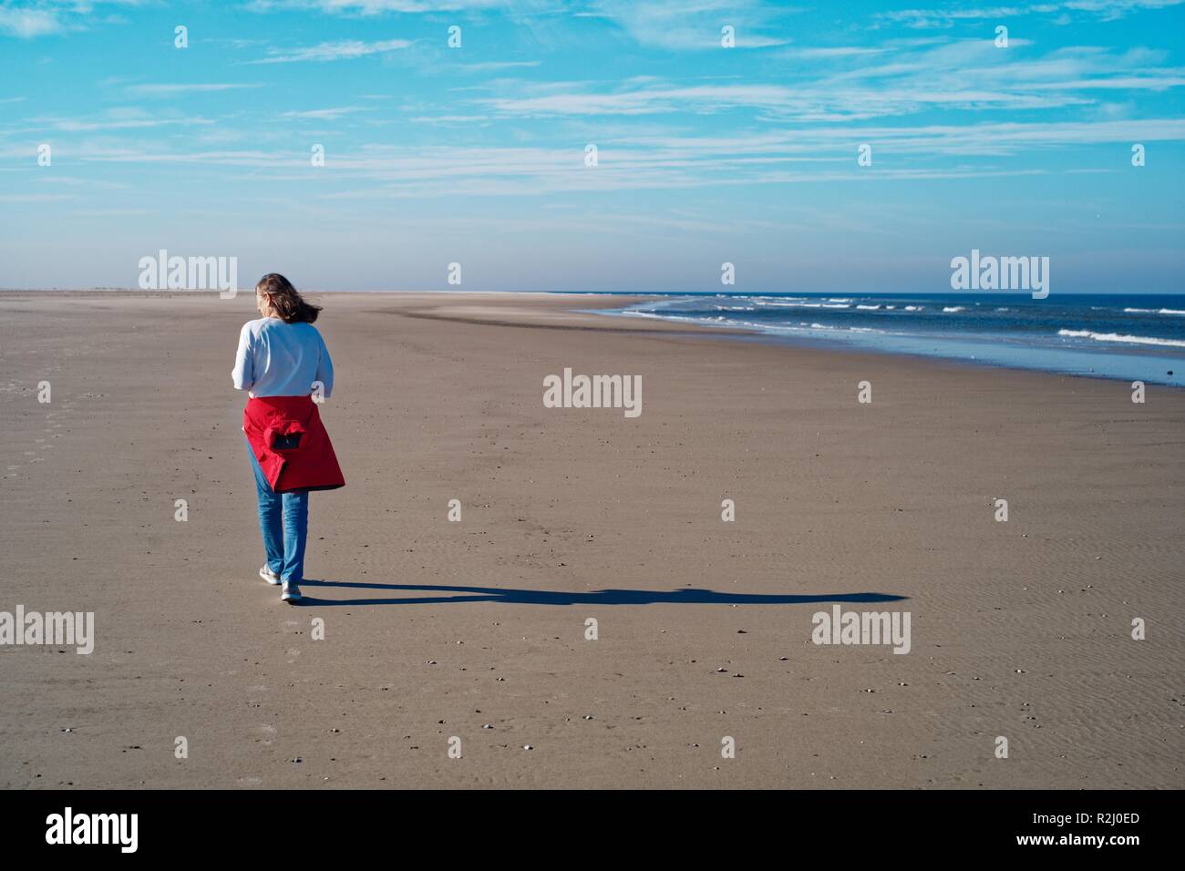 Donna camminando lungo la spiaggia in autunno, Juist, Frisia orientale, Bassa Sassonia, Germania Foto Stock