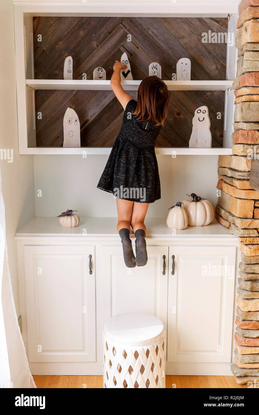 Ragazza mettendo su Halloween decorazioni fantasma Foto Stock