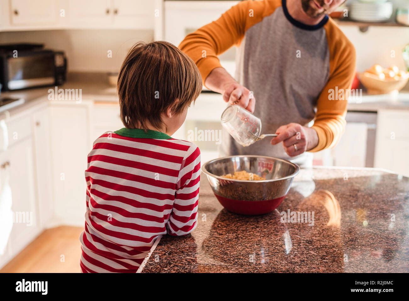 Ragazzo aiutando il padre cuocere in cucina Foto Stock