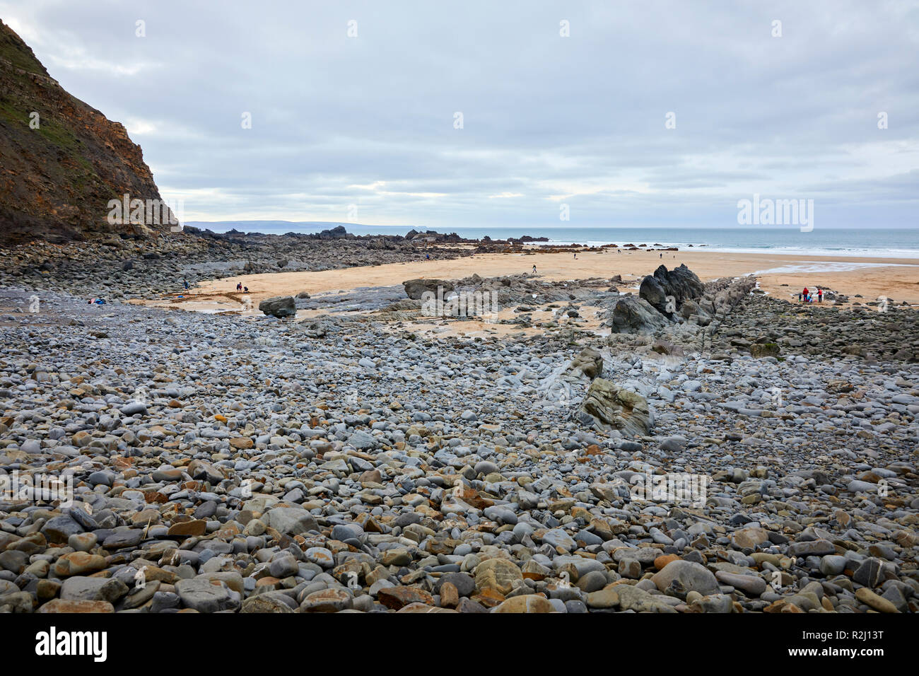 I vacanzieri su un giorno nuvoloso con la bassa marea sulla baia Duckpool. Bude, Cornwall Foto Stock