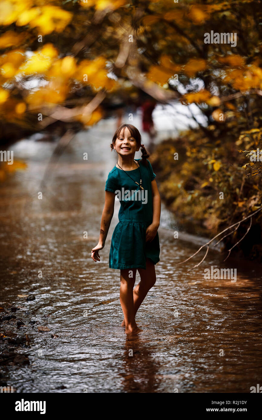 Sorridente ragazza camminare in un bosco creek, Stati Uniti Foto Stock
