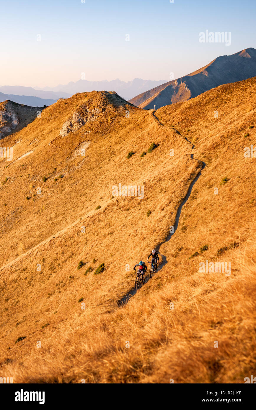 L uomo e la donna in mountain bike nelle alpi austriache al tramonto vicino a Gastein, Salisburgo, Austria Foto Stock