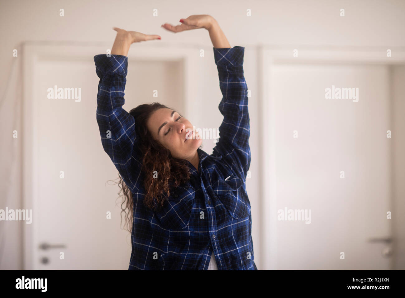 Donna in piedi nel soggiorno stretching Foto Stock