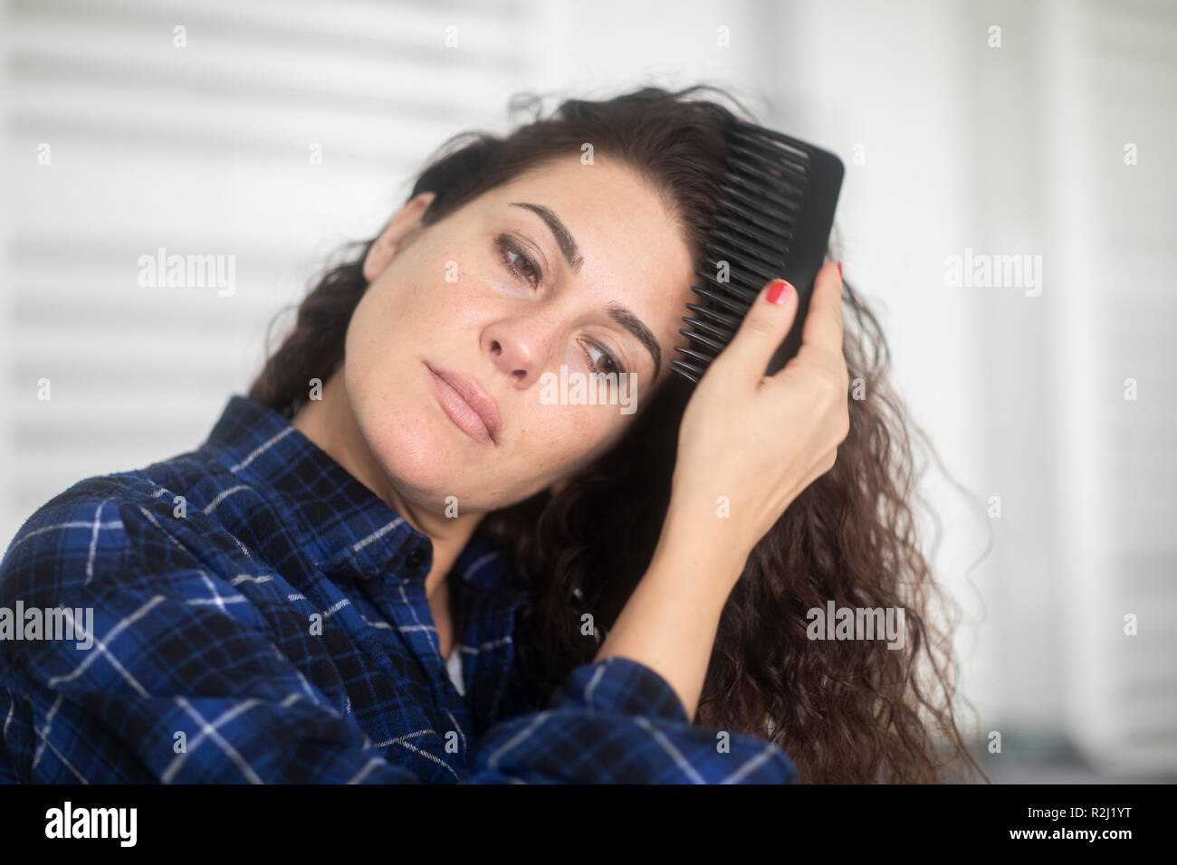 Donna in piedi in bagno pettinare i capelli Foto Stock