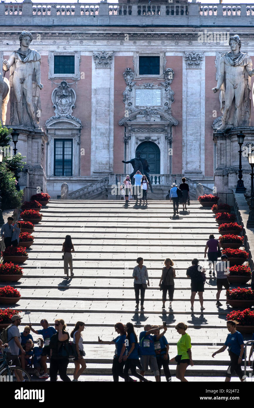 I turisti sui gradini che conducono alla Piazza del Campidoglio e i Musei Capitolini, sulla sommità del colle capitolino, guardando verso la facciata del Foto Stock