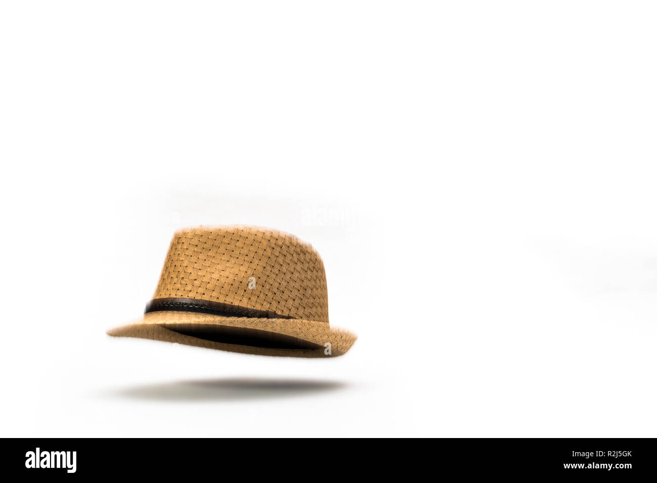 Alla caduta di un cappello. Una paglia panama hat cadere contro uno sfondo bianco. Foto Stock