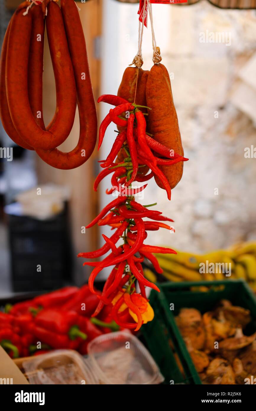 Red chilis appeso su un mercato mediterraneo in stallo Foto Stock