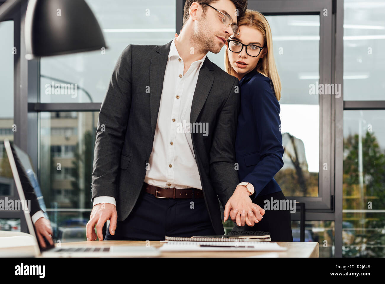 Giovani imprenditori tenendo le mani mentre flirtare al posto di lavoro Ufficio concetto romantico Foto Stock