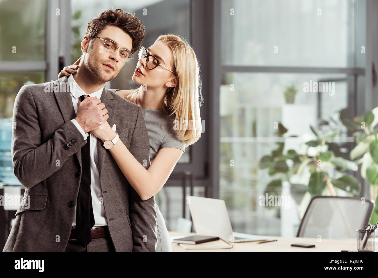 Bella imprenditrice abbracciando elegante uomo d affari in ufficio, flirtare e ufficio concetto romantico Foto Stock