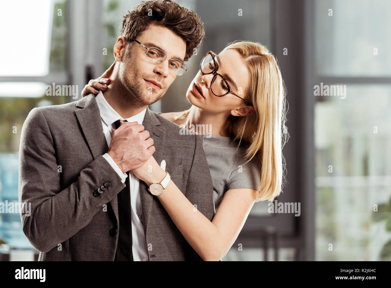 Ritratto di bella imprenditrice abbracciando elegante uomo d affari in ufficio, flirtare e ufficio concetto romantico Foto Stock