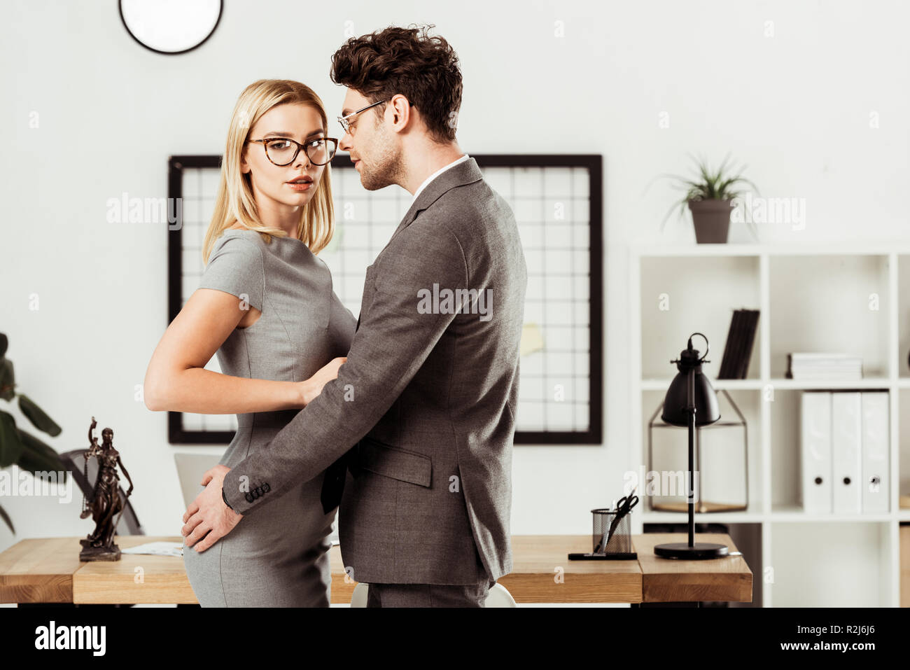 Giovani avvocati che abbraccia ogni altro mentre sono in piedi in ufficio, flirtare e ufficio concetto romantico Foto Stock