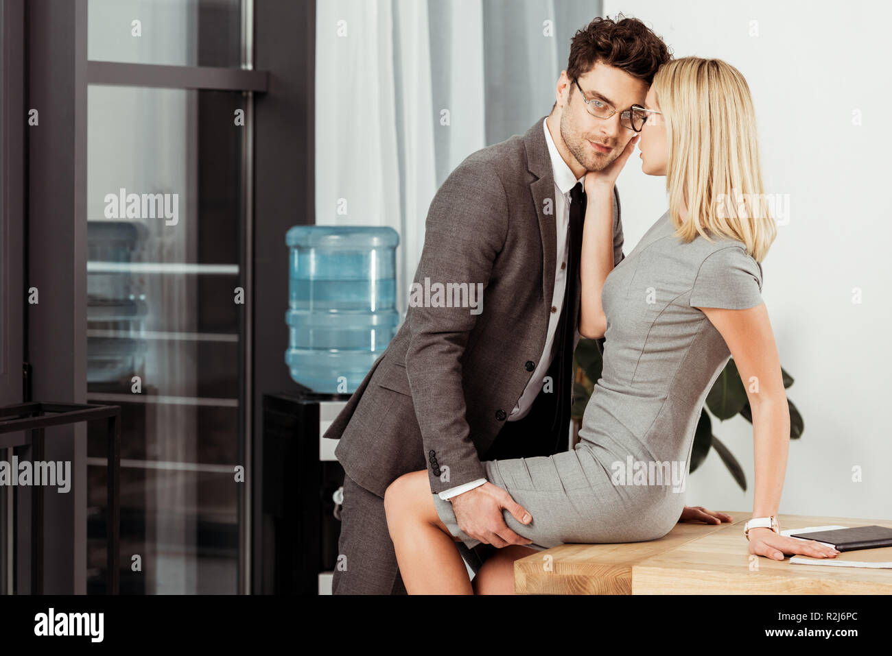 Vista laterale dei colleghi di lavoro flirtare al lavoro in ufficio, offirce romanticismo concetto Foto Stock