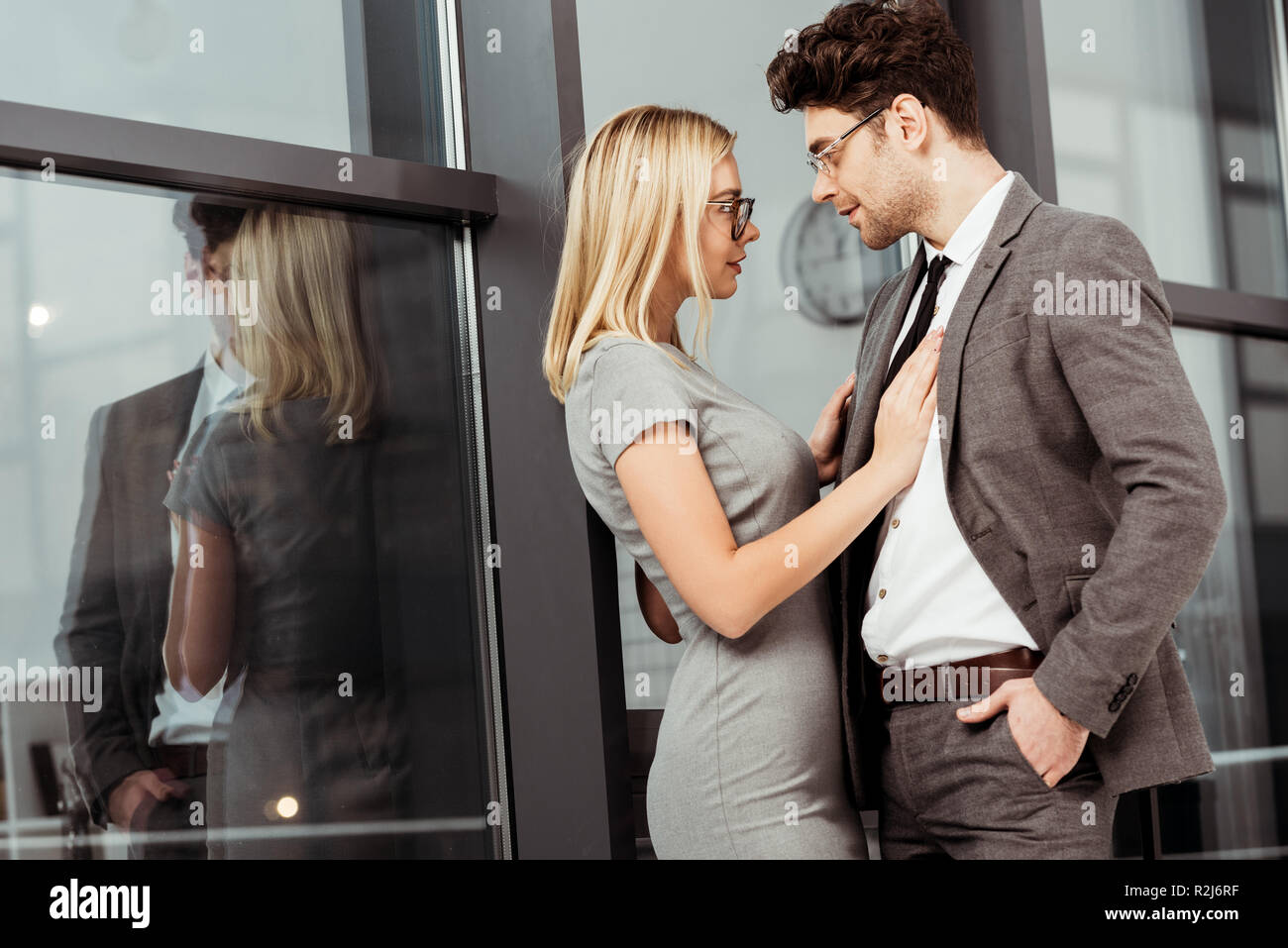 Vista laterale del businessman abbracciando e guardando ogni altro in ufficio, flirtare e ufficio concetto romantico Foto Stock