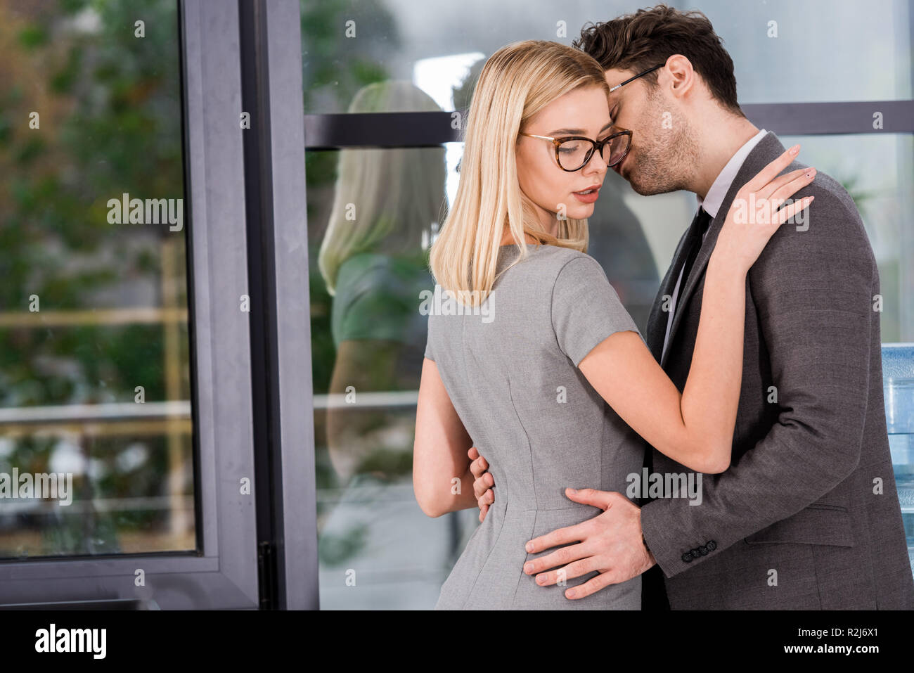 Vista laterale del businessman abbracciando in ufficio, flirtare e ufficio concetto romantico Foto Stock