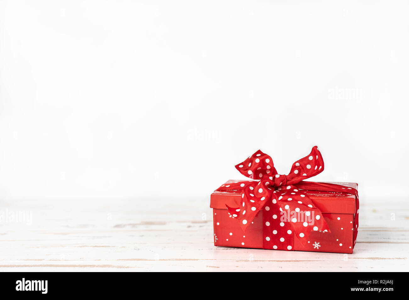 Natale Rosso confezione regalo con un grande fiocco rosso su sfondo bianco. Spazio di copia Foto Stock