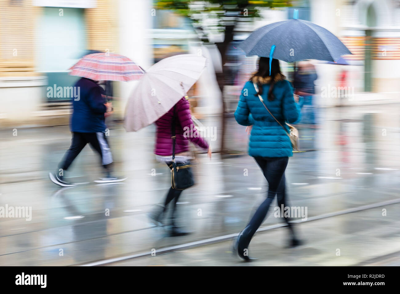 Persone con ombrelloni a camminare in città in un giorno di pioggia, foto fatta con motion blur effetto Foto Stock