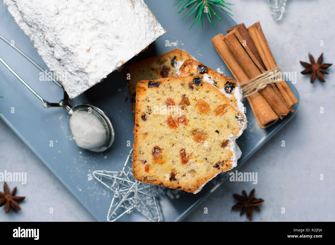 Frutta e dado di torta di pane spolverata con zucchero a velo, le vacanze di Natale ed invernali trattare, torte fatte in casa con uvetta su sfondo grigio Foto Stock