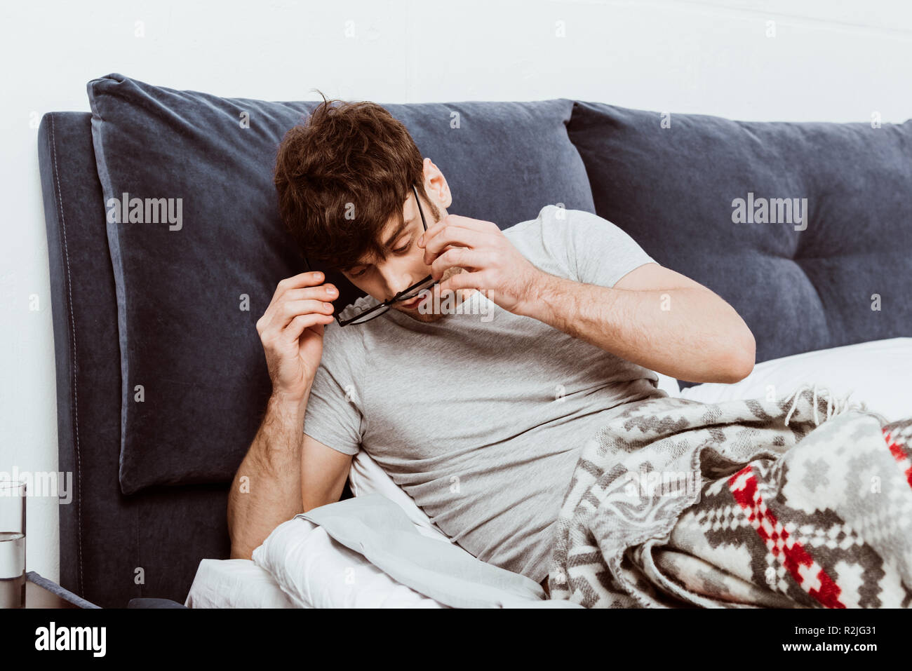 L'uomo il risveglio e la messa su occhiali durante la mattina tempo nel letto di casa Foto Stock