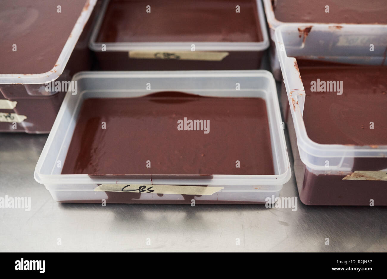 Il cioccolato fuso in vassoi su una confetteria rendendo tabella di fabbrica Foto Stock