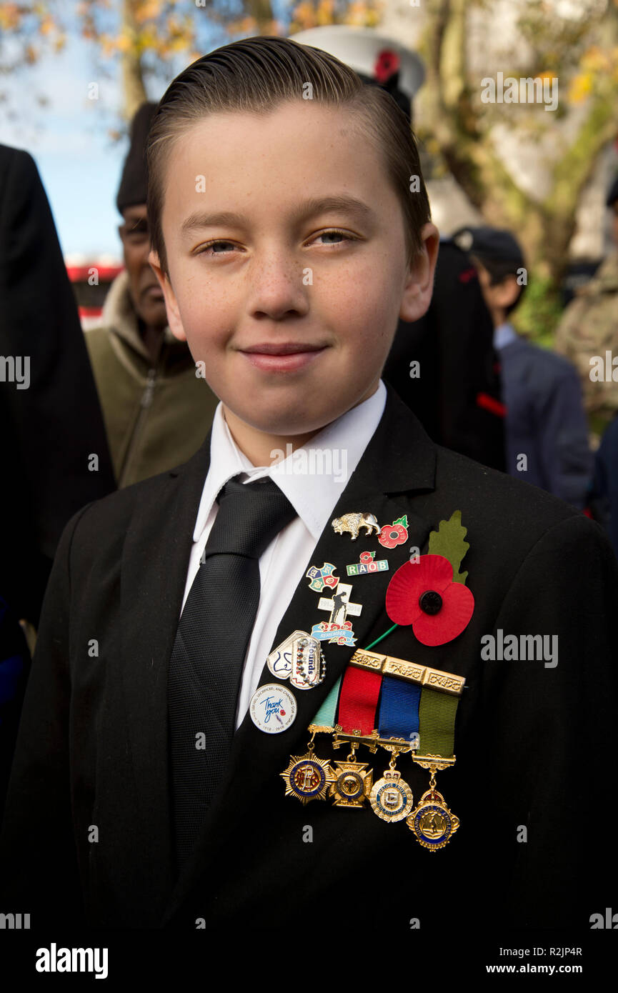 Giorno del Ricordo corona la posa di San Giovanni a Hackney chiesa. Un giovane ragazzo indossa il suo nonno e medaglie. Foto Stock