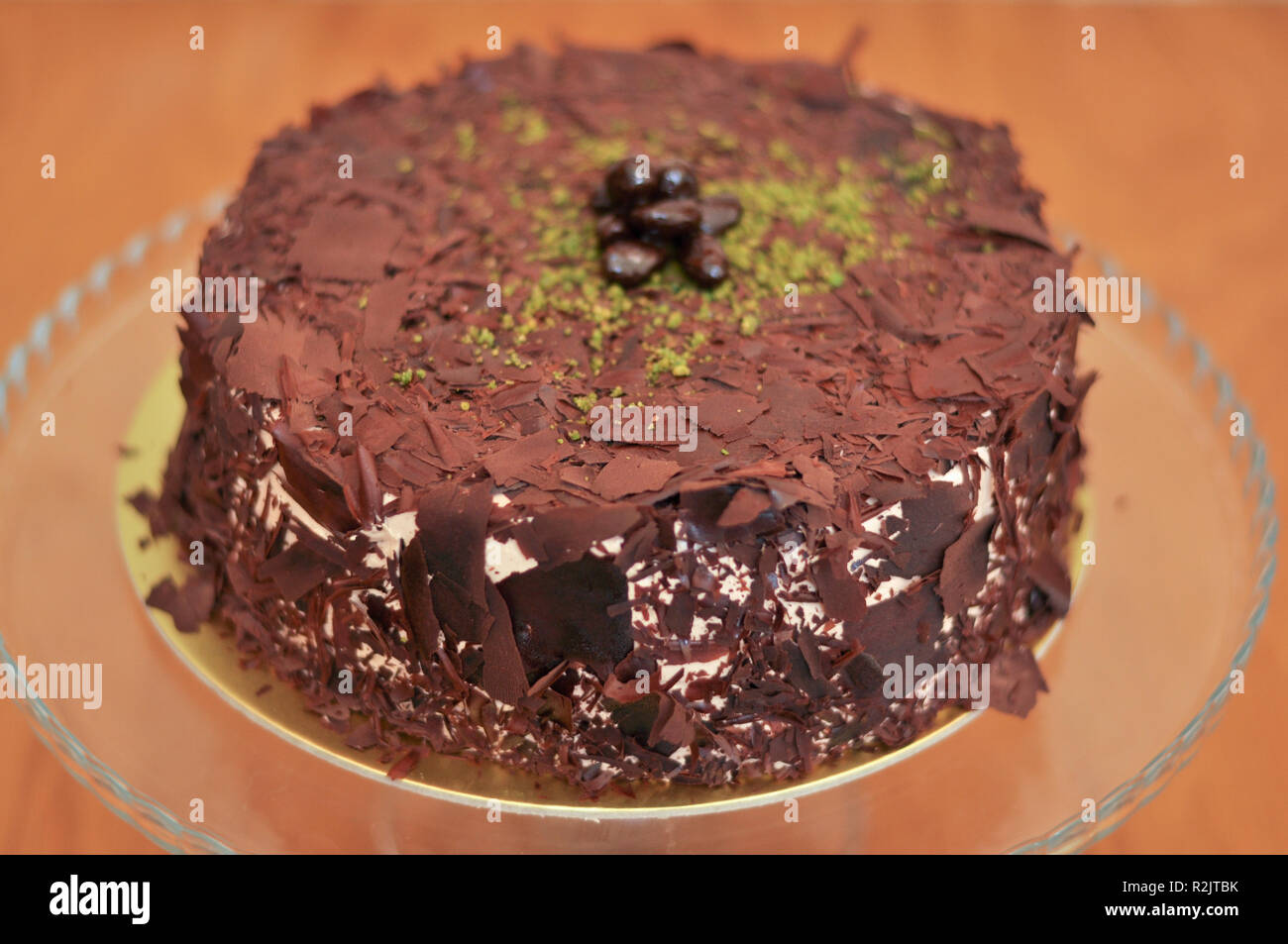 Delizioso cioccolato fresco Pistaccio torta con pezzetti di cioccolato intorno e pistacchi e servite sulla piastra di vetro con decorazione di Natale Foto Stock