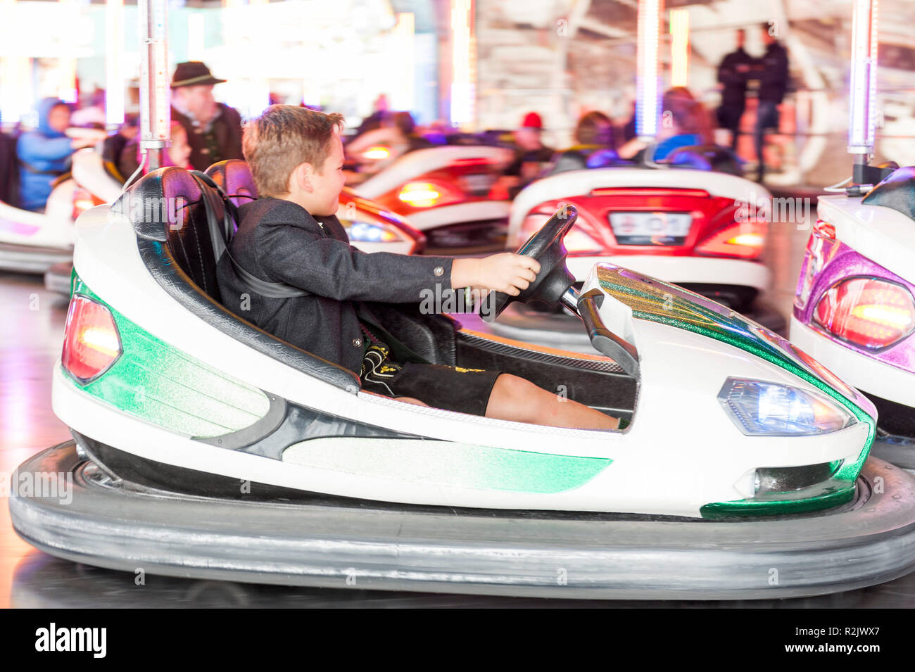 Dieci-anno-vecchio ragazzo in abiti tradizionali la guida bumper car, Monaco di Baviera, Oktoberfest Foto Stock