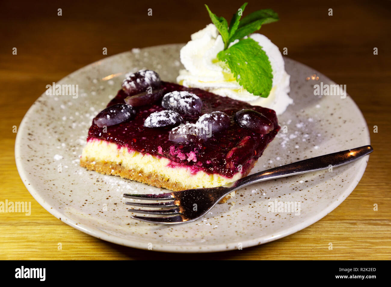 Cheesecake servita con panna. La cheesecake è guarnita con frutta e servito con la menta-sormontato crema. Foto Stock