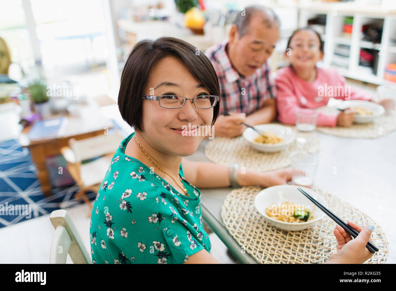 Ritratto di donna sorridente mangiare tagliatelle con la famiglia a tavola Foto Stock