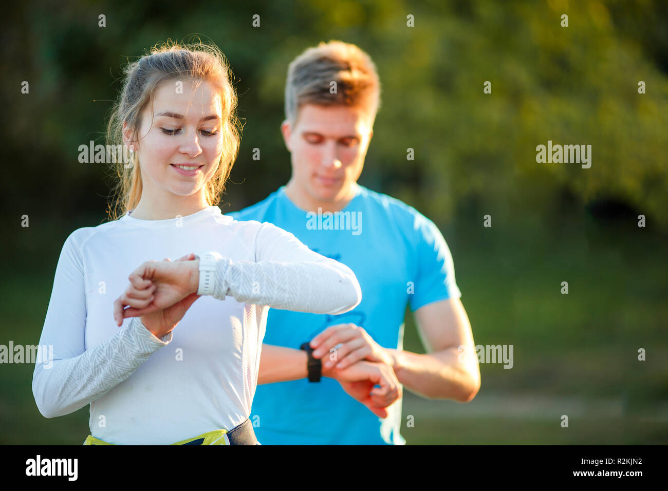 Foto della coppia di atleti guardando orologio nel parco sul giorno di estate Foto Stock