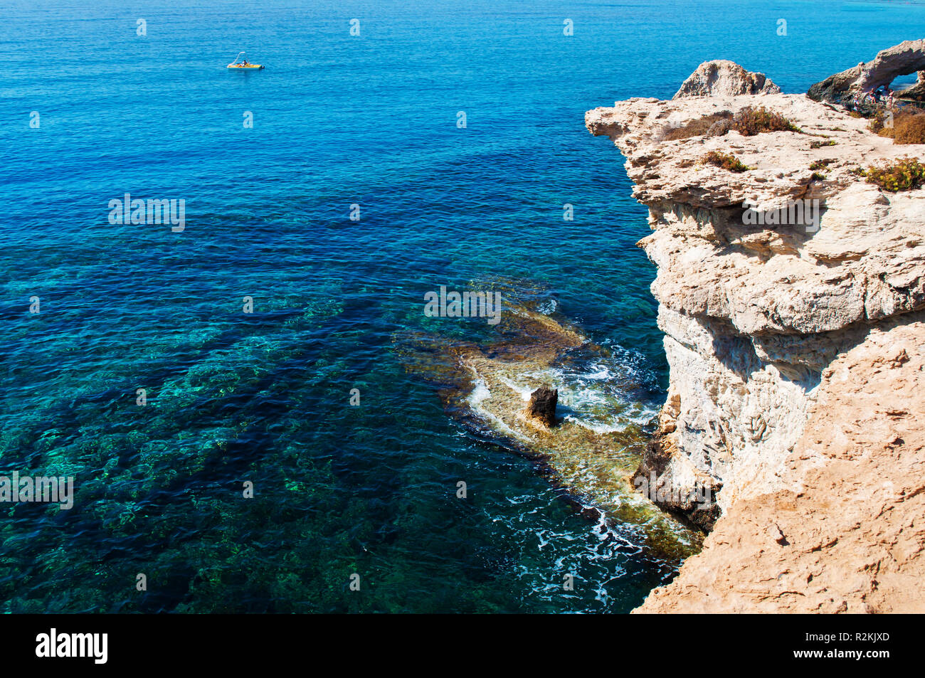 Una barca catamarano sullo sfondo di giallo e pietra bianca scogliera vicino increspata trasparente crystal clear incredibile verde e blu dell'acqua. Il caldo estivo Foto Stock