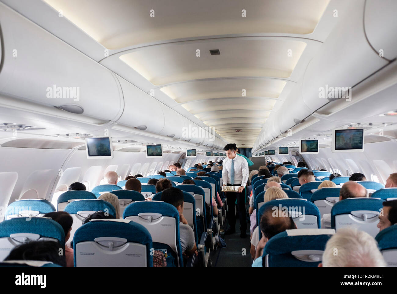 Steward che serve bevande ai passeggeri in classe economica sedi sul Vietnam Airlines volo da Danang a Ho Chi Minh City. Vietnam Asia Foto Stock