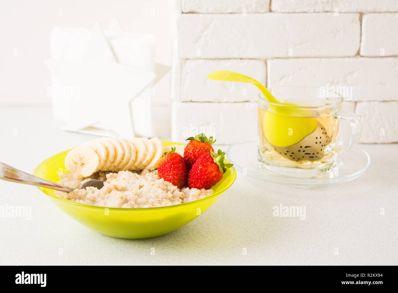 Sana colazione con fiocchi d'avena, banana e fragola, sfondo luminoso Foto Stock