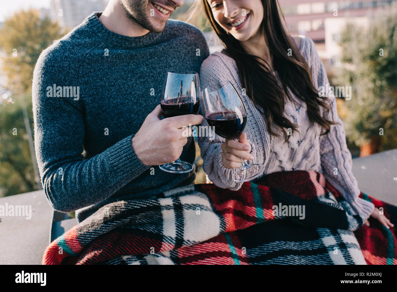 Ritagliato colpo di Bella coppia Giovane che copre in plaid e bere il vino rosso sul tetto Foto Stock