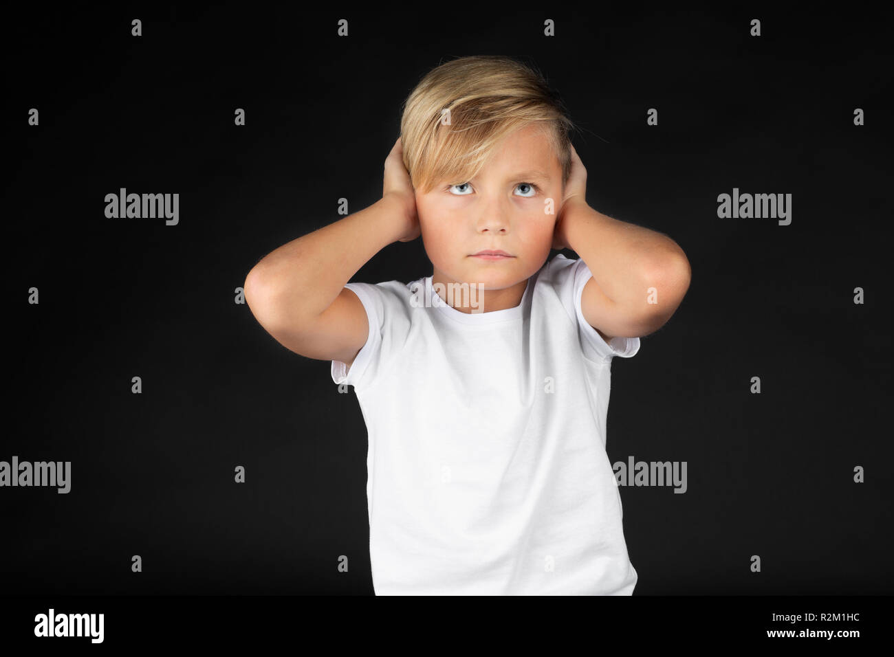 Piccolo ragazzo biondo copre le sue orecchie Foto Stock