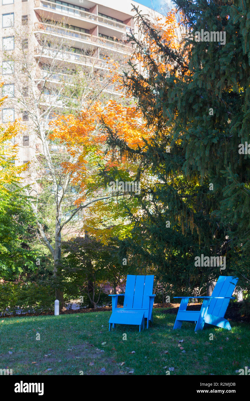 Posti a sedere all'aperto blu nel parco urbano con edificio di appartamenti sullo sfondo, Crystal City Water Park, Arlington, Virginia, Stati Uniti Foto Stock