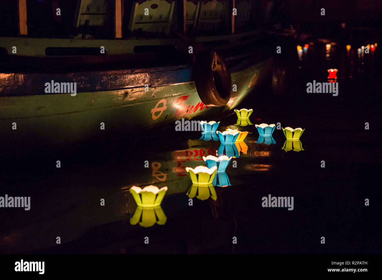 Candele galleggianti, drifting su un fiume vicino ad una barca durante il mondo Earth Hour, Hoi An, Vietnam Foto Stock