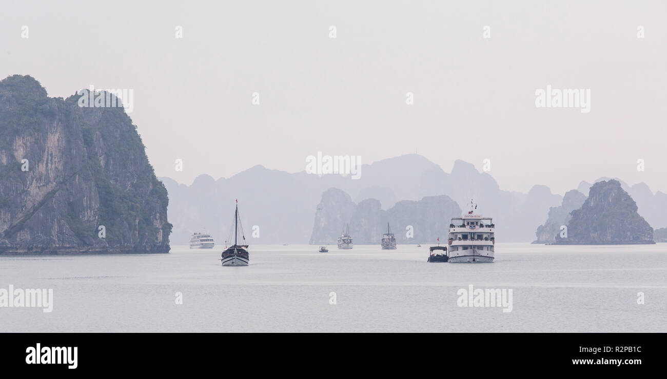 Foggy Halong Bay, diverse le barche in acqua, circondato da scogliere calcaree, panorama, monocromatico Foto Stock