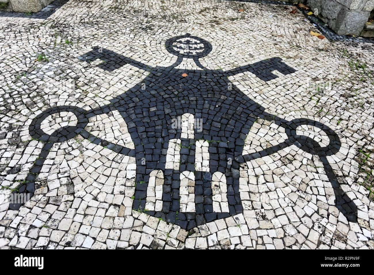 Parte del pavimento del cortile di una regione del nord della chiesa in Portogallo con simboli cristiani. Pavimentazione portoghese, lo stile di un tradizionale stile di pavimentazione usato in pe Foto Stock