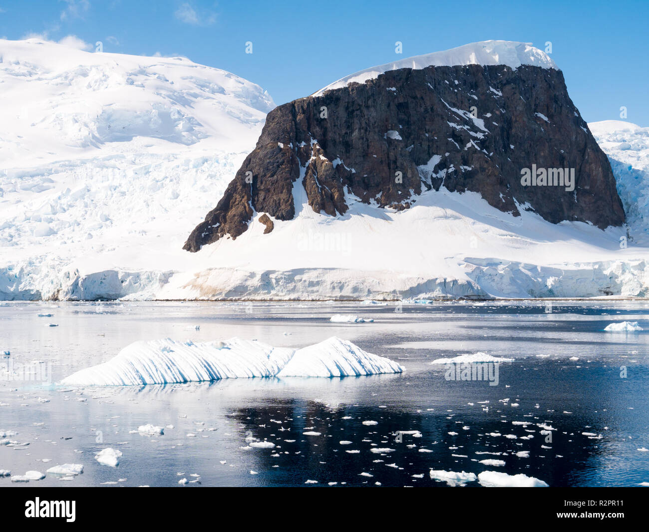 Snow capped mountain di Danco isola sulla soleggiata giornata estiva con cielo blu nel canale Errera, Penisola Antartica, Antartide Foto Stock